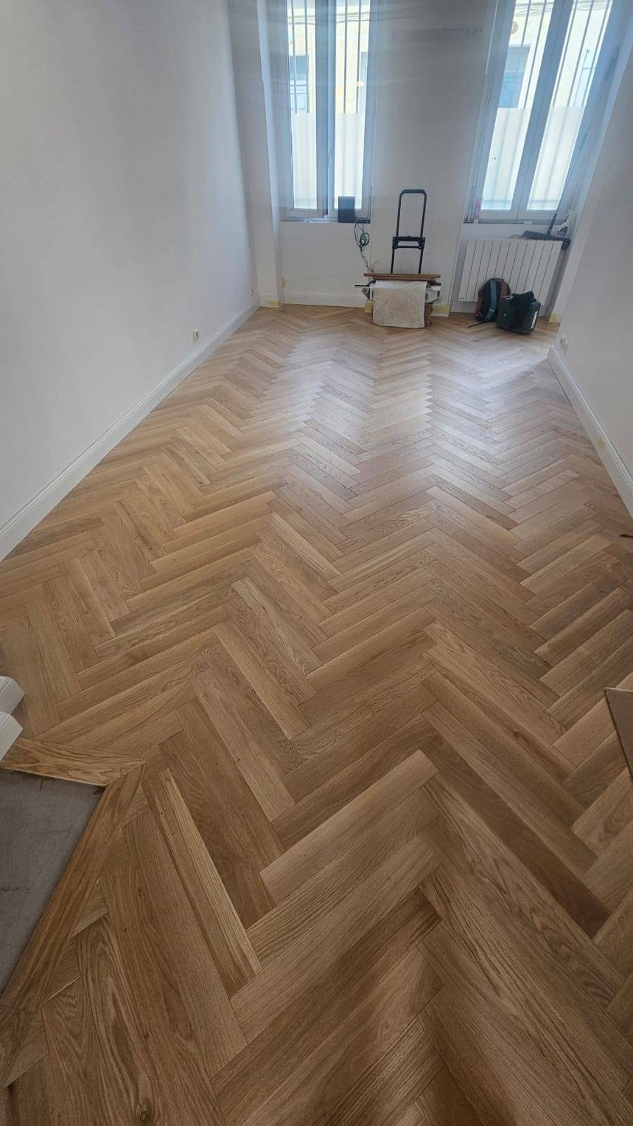 Détail de la pose collée d’un parquet chêne en motif bâton rompu dans une résidence bordelaise.