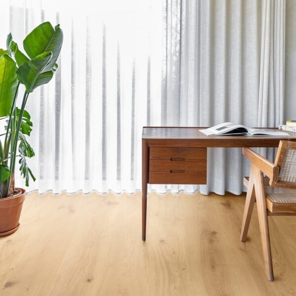 Bureau design en bois foncé près d'une fenêtre aux rideaux blancs. Le sol est recouvert d'un parquet chêne clair.