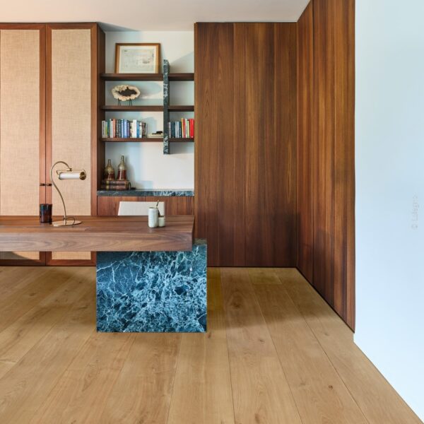 Bureau minimaliste en noyer et marbre bleu. Mur lambrissé et armoires intégrées. Plancher en chêne clair. Lampe de bureau en laiton.