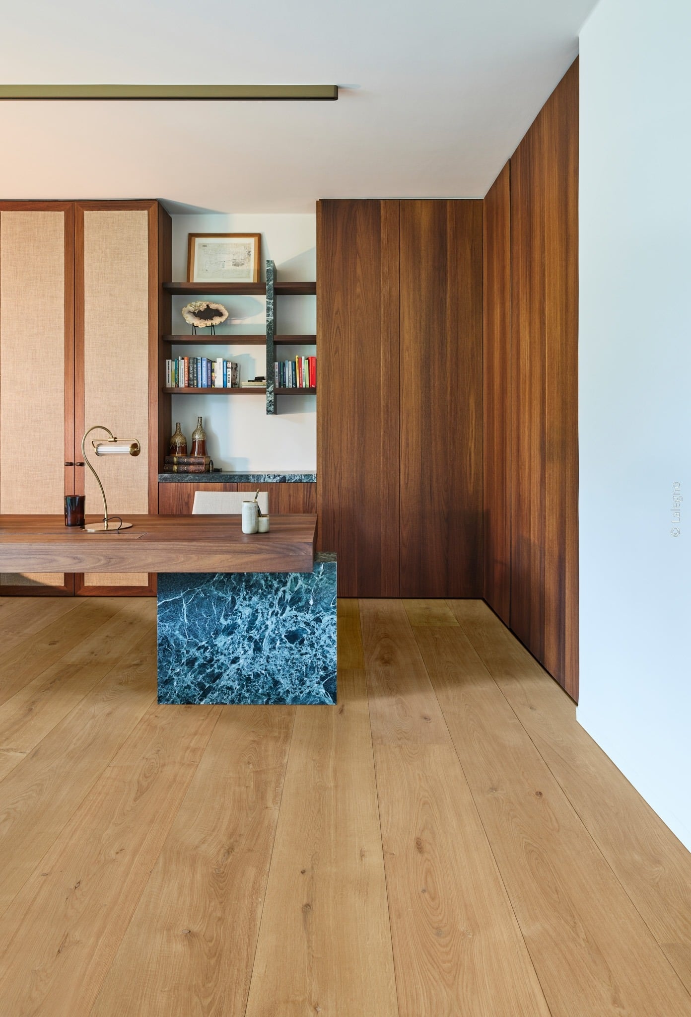 Bureau minimaliste en noyer et marbre bleu. Mur lambrissé et armoires intégrées. Plancher en chêne clair. Lampe de bureau en laiton.