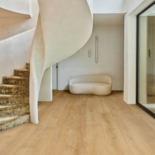 Hall d'entrée minimaliste avec escalier en colimaçon brutaliste et marches en pierre. Canapé organique sur plancher bois clair.