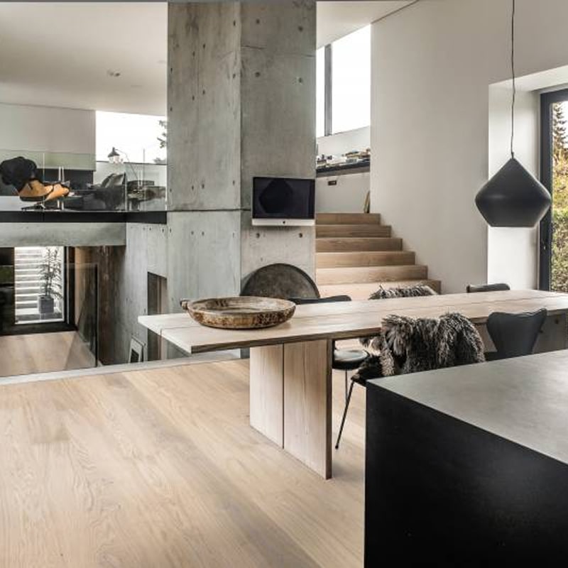 Béton et bois : Design industriel pour salle à manger moderne. Salle à manger design industriel/Scandinave. Table bois clair, chaises fourrure, colonne béton. Vue mezzanine salon et escalier bois.