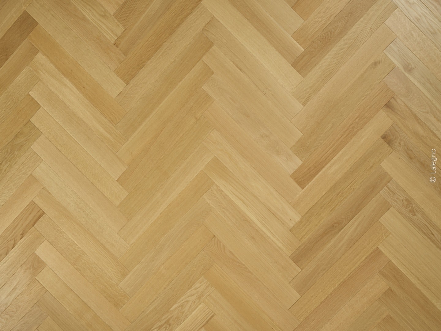 Parquet en bois de chêne clair posé en bâtons rompus (herringbone). Texture naturelle et finition mate. © Lalegno visible.