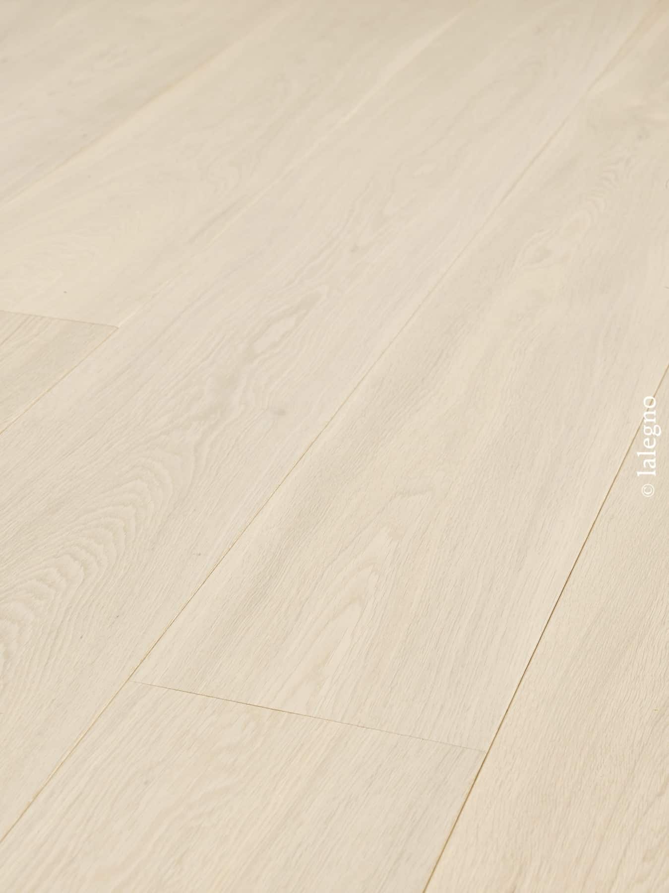 Revêtement de sol en parquet chêne blanchi, lames larges. Couleur bois très clair, grain visible, pose en diagonale.