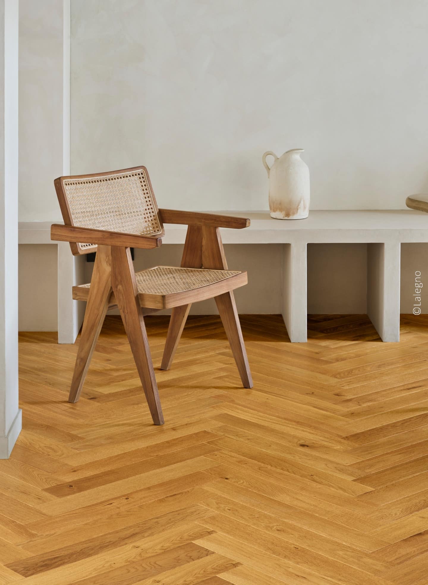 Chaise en bois et cannage, design minimaliste, devant un banc en béton. Sol en parquet chêne clair posé en chevrons. © Lalegno.