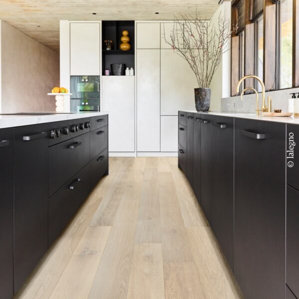 Cuisine galerie luxueuse : îlots noirs mats, comptoirs clairs, sol en parquet de chêne blanchi. Rangement intégré. (c) lalegno.