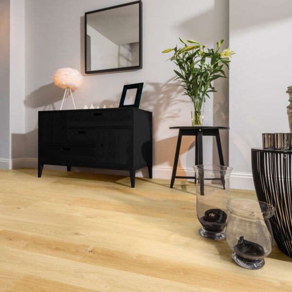Parquet chêne clair naturel, posé dans une entrée moderne. Le sol chaud contraste avec le mobilier noir ébène et les murs gris.