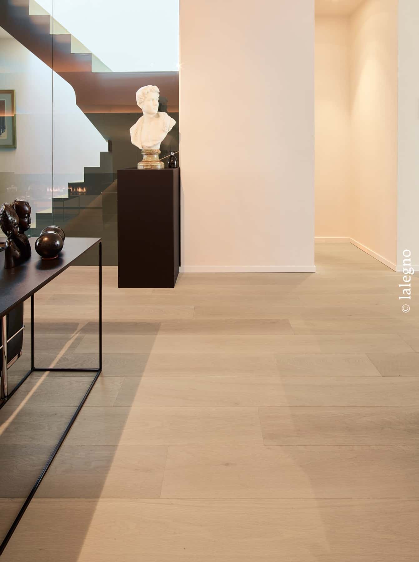 Parquet chêne clair Lalegno dans un hall moderne. Buste en marbre sur socle noir près d'un escalier en verre.