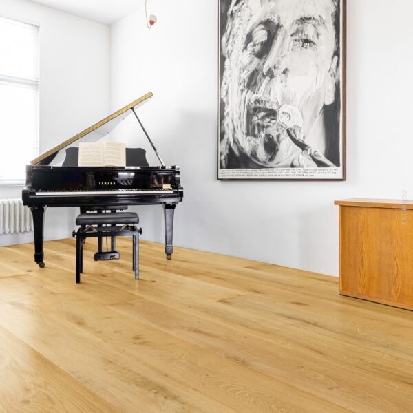 Grand piano à queue Yamaha noir dans un salon minimaliste. Parquet de chêne clair et œuvre d'art portrait noir et blanc imposante.
