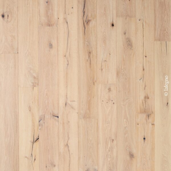 Parquet en chêne clair brossé à lames larges, aspect rustique avec nœuds et fissures foncées. Texte : © lalegno.