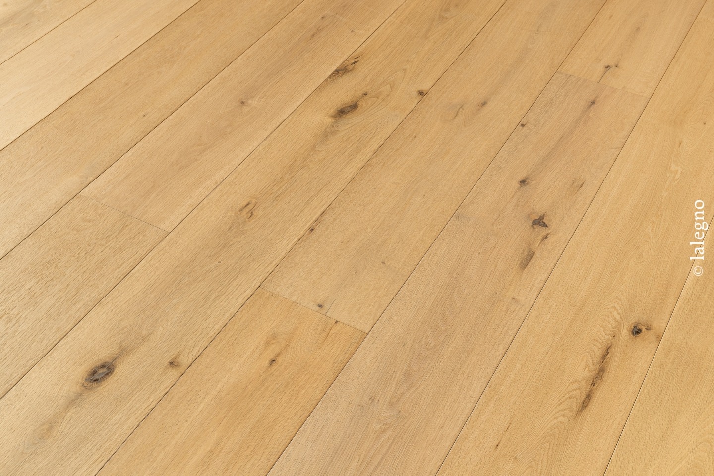 Plancher chêne naturel clair, lames larges rustiques avec nœuds. Pose diagonale. Copyright visible : lalegno.