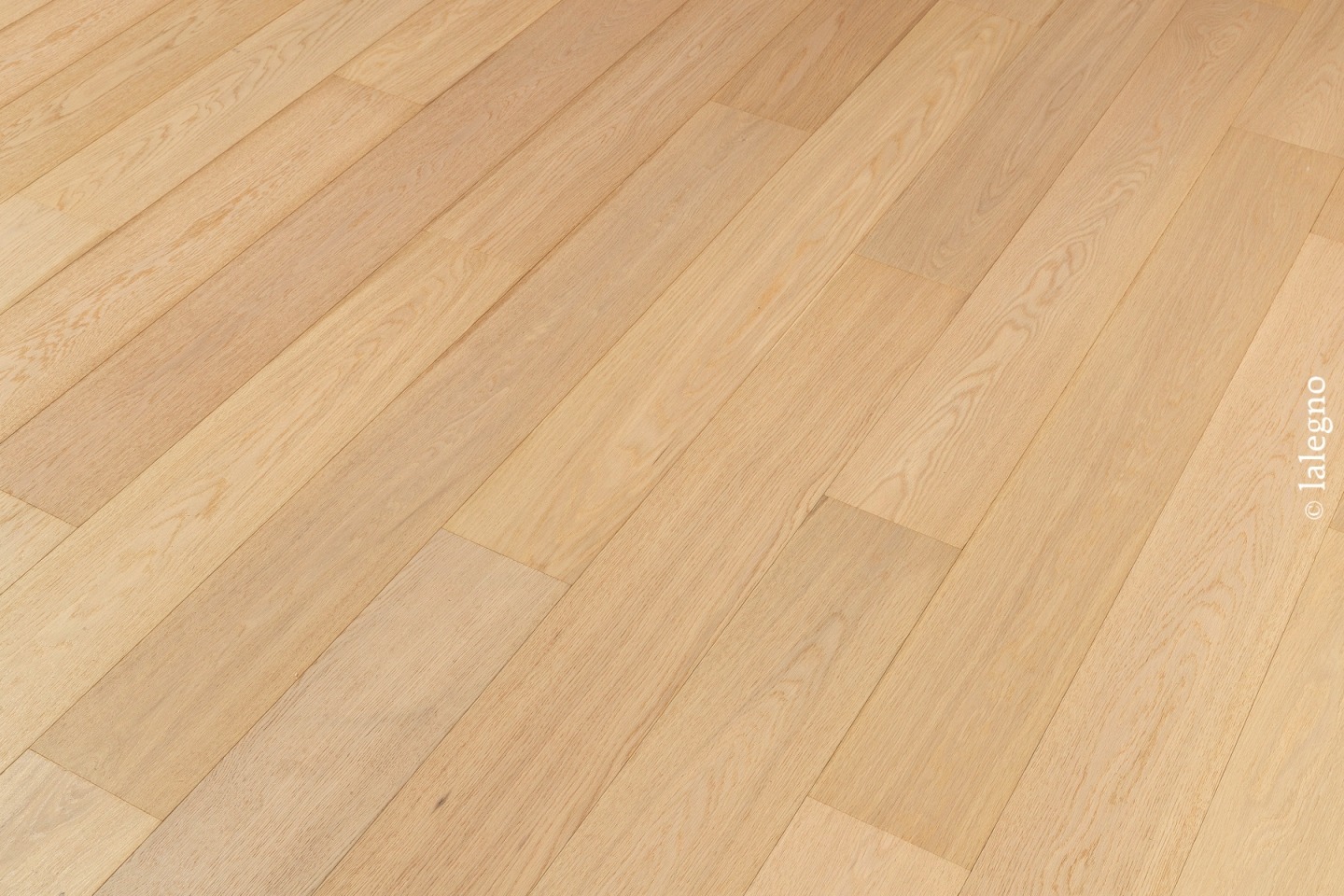 Parquet en chêne clair naturel, lattes larges posées en diagonale pour un revêtement moderne. Finition mate.