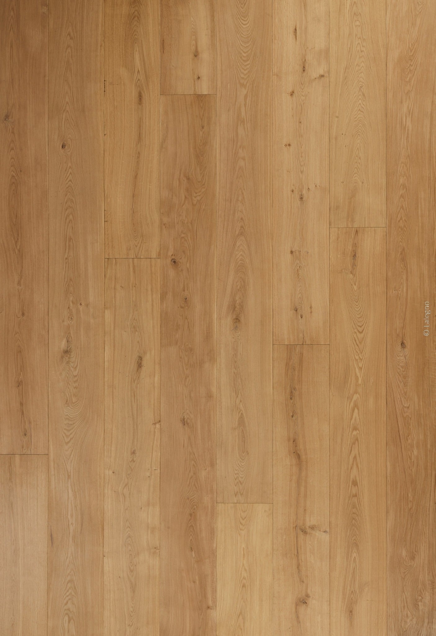 Sol en parquet de chêne clair, lames larges à pose droite, texture naturelle et nœuds discrets. Grain du bois visible. © Lalegno.