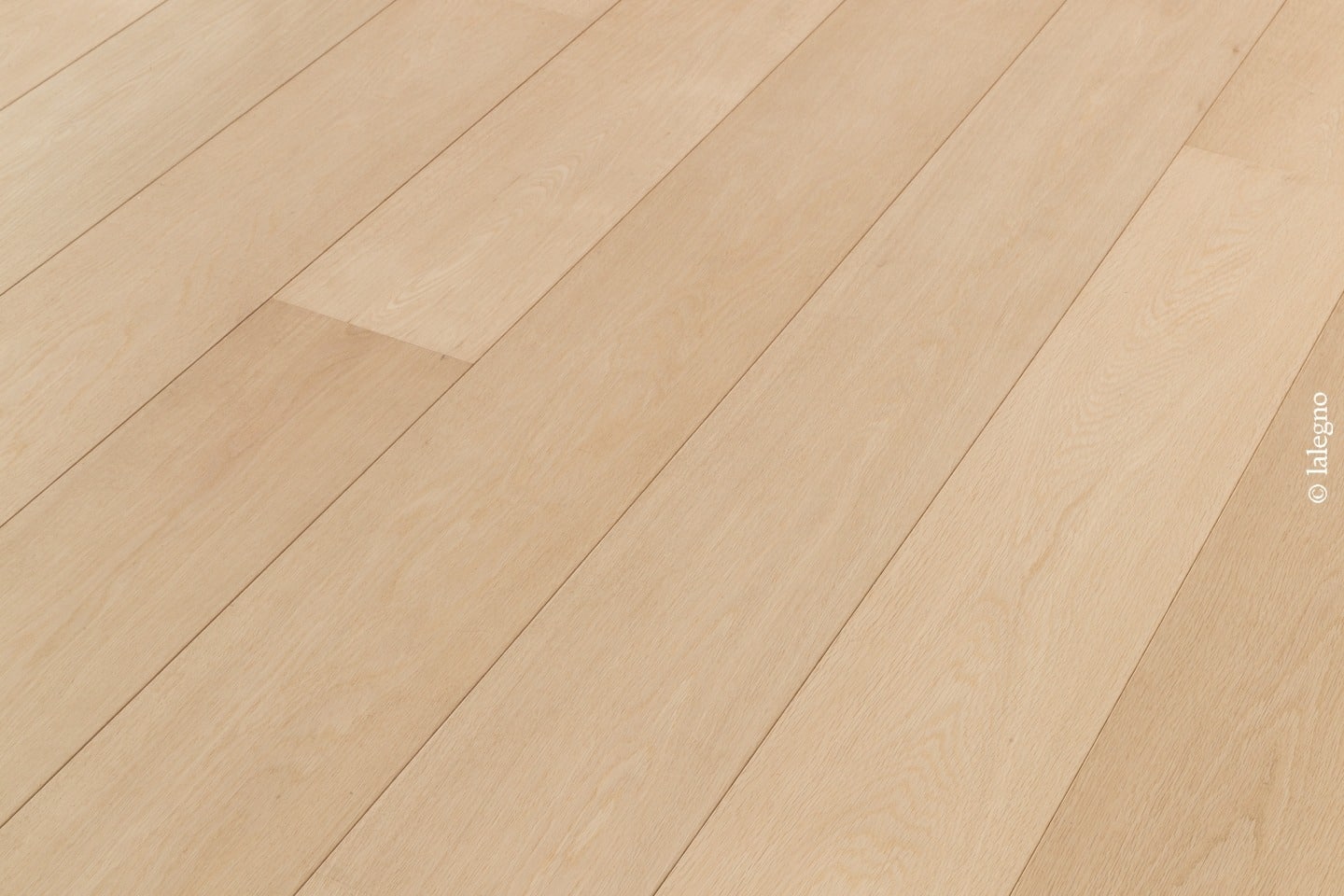 Larges planches de parquet en chêne blond, texture lisse et grain subtil, posées en diagonale.