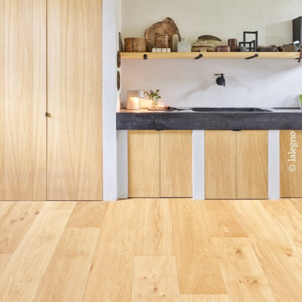 Parquet chêne clair, larges lames. Aménagement intérieur rustique chic avec hauts placards bois et petite cuisine minimaliste en pierre noire.
