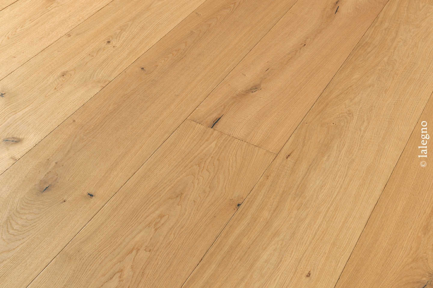 Plancher en chêne, lames larges claires posées en diagonale, montrant le grain et des nœuds discrets. Copyright lalegno.