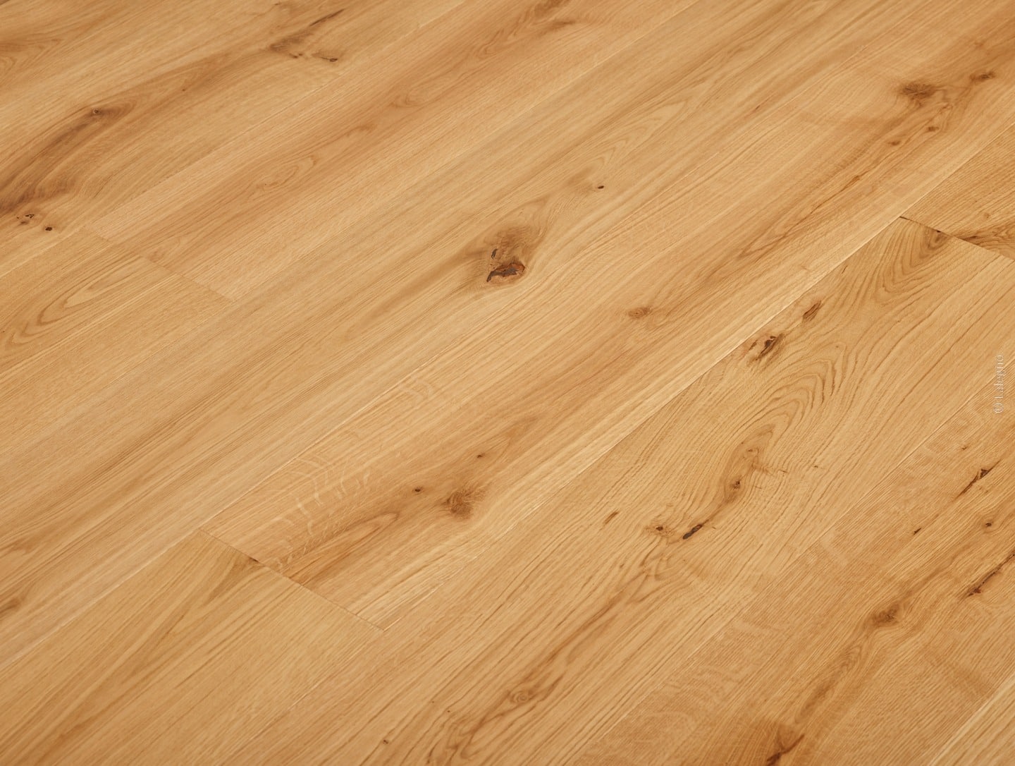 Plancher en chêne massif clair, posé en diagonale. Lames longues présentant des veines de bois naturelles et des nœuds foncés marqués.