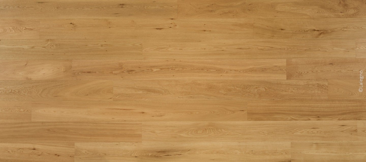 Plancher en bois de chêne clair à lames larges posées en coupe de pierre, présentant un grain naturel et chaud. Marque Lalegno.