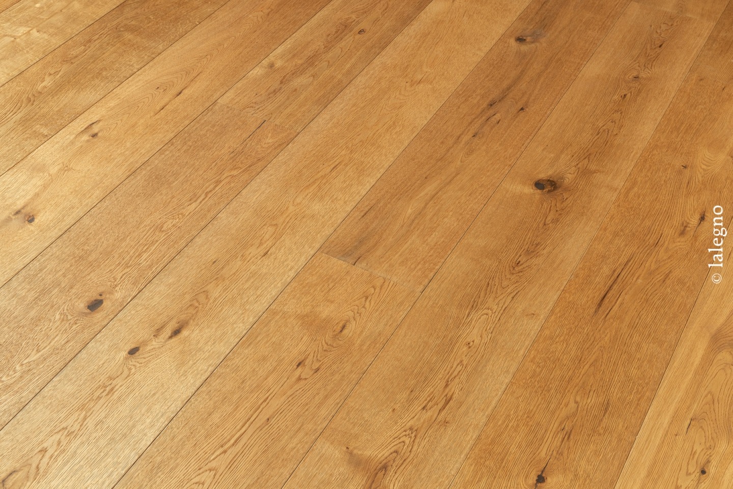 Parquet chêne rustique à lames larges, teinte dorée miel, avec nœuds marqués, posé en diagonale. Copyright : © lalegno.