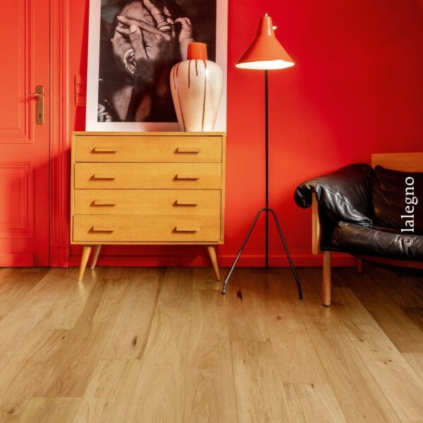 Parquet chêne clair à larges lattes dans un intérieur audacieux. Mur rouge vif contrastant avec une commode Mid-century et une œuvre d'art encadrée.