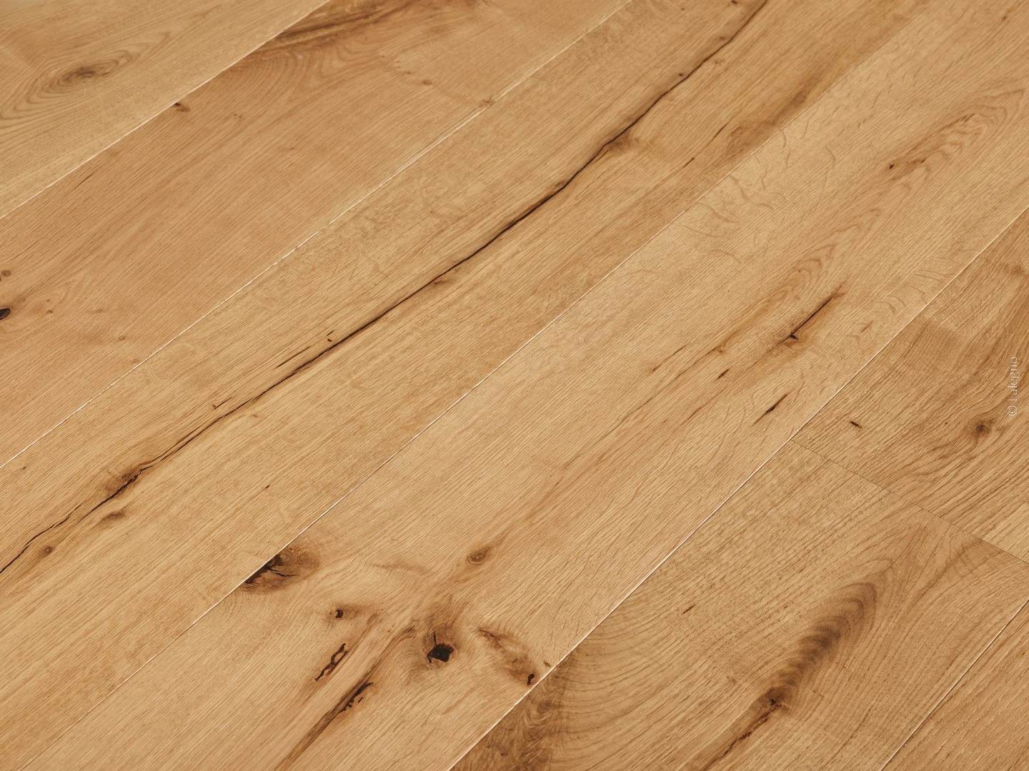 Parquet chêne rustique lames larges, couleur miel, avec nœuds et fissures noires prononcées. Plancher bois brut et naturel.