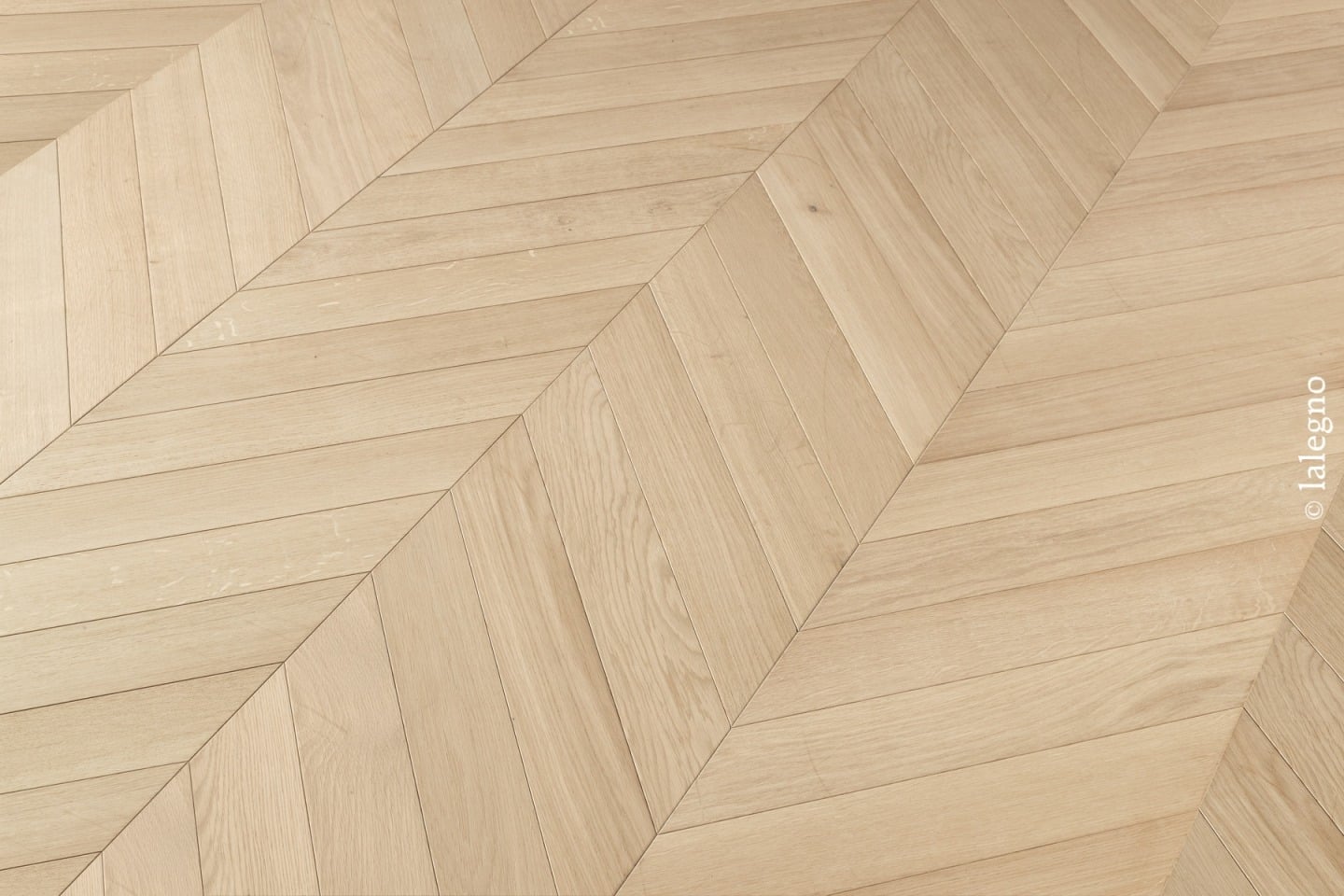 Parquet en chêne clair, motif chevron moderne. Texture et grain du bois visibles. Texte : © lalegno.