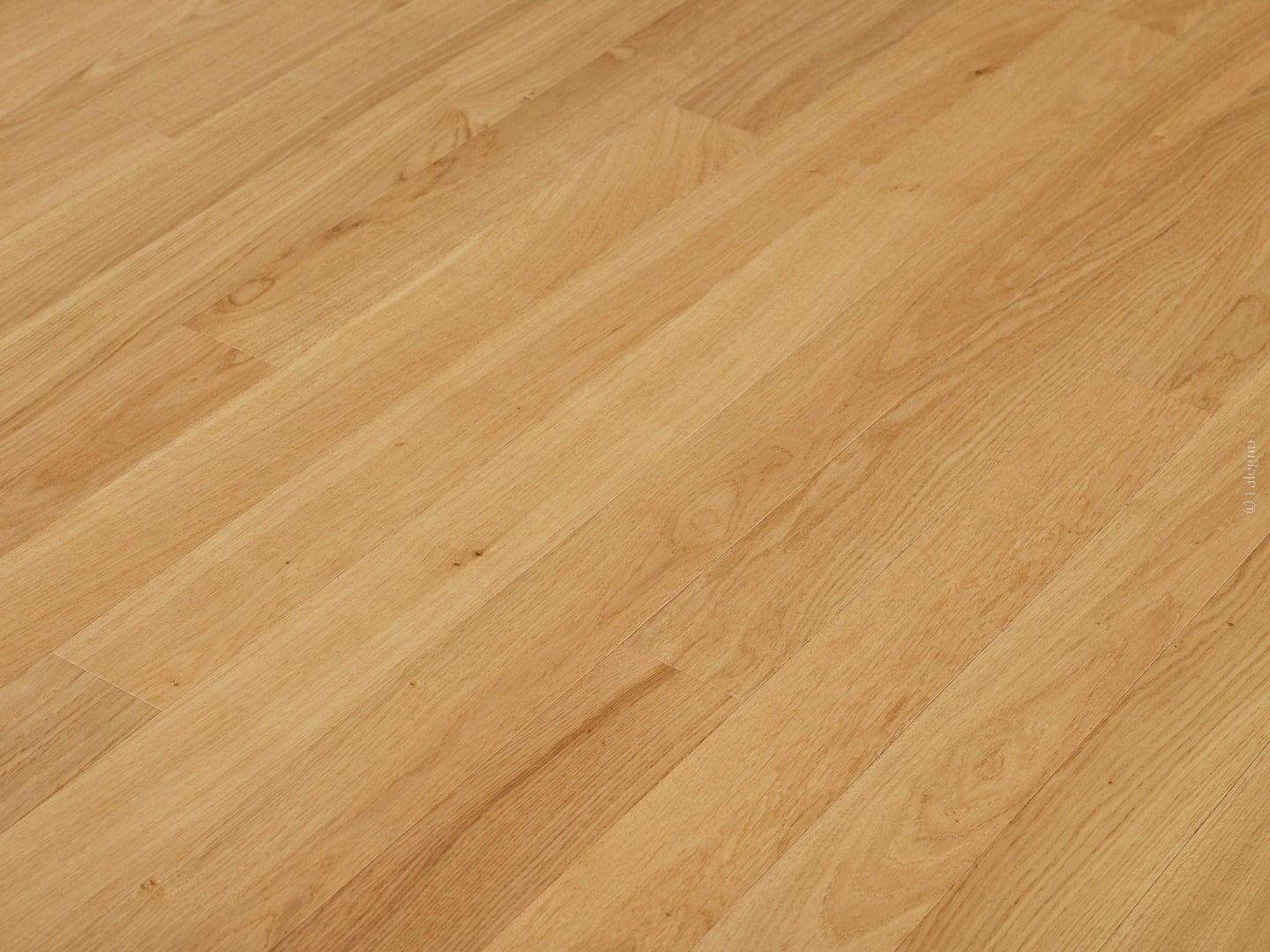 Sol en lames de bois chêne clair. La pose diagonale met en valeur le grain et la teinte miel naturelle du revêtement.