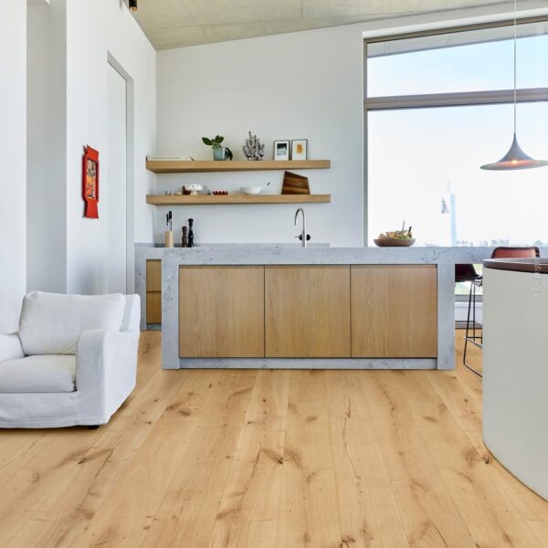 Intérieur moderne et lumineux. Plancher bois chêne rustique et nervuré contrastant avec l'îlot central en béton et les murs blancs.