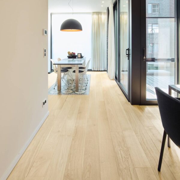 Plancher bois clair chêne dans un appartement moderne. Couloir menant à la salle à manger, grande suspension noire, portes vitrées coulissantes.