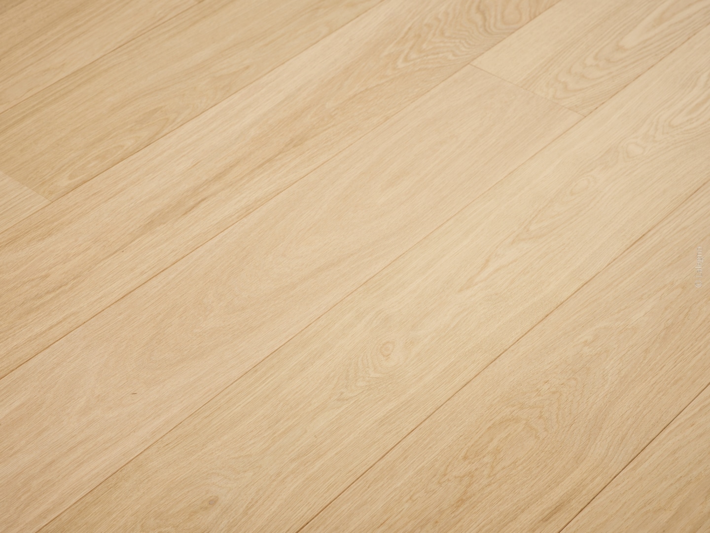 Plancher en bois clair de chêne naturel, avec des lames longues posées en diagonale, montrant la texture douce du bois.