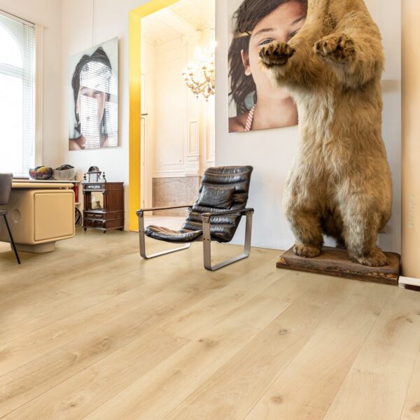 Grandes planches de plancher en bois clair sous un ours brun taxidermie rugissant, près d'un fauteuil moderne en cuir noir.