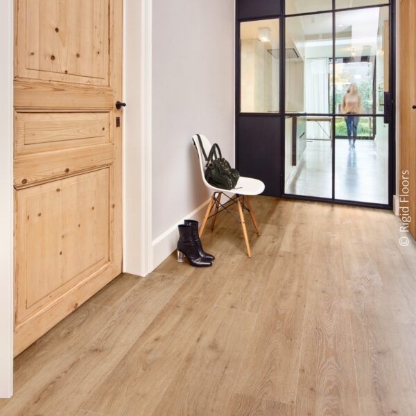 Plancher aspect chêne naturel clair dans un couloir élégant. Décoration avec porte vitrée noire industrielle, porte en pin et chaise blanche.