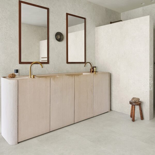 Salle de bain minimaliste. Carrelage grand format effet pierre murs et sol, double vasque terracotta incurvée, robinets laiton brossé.