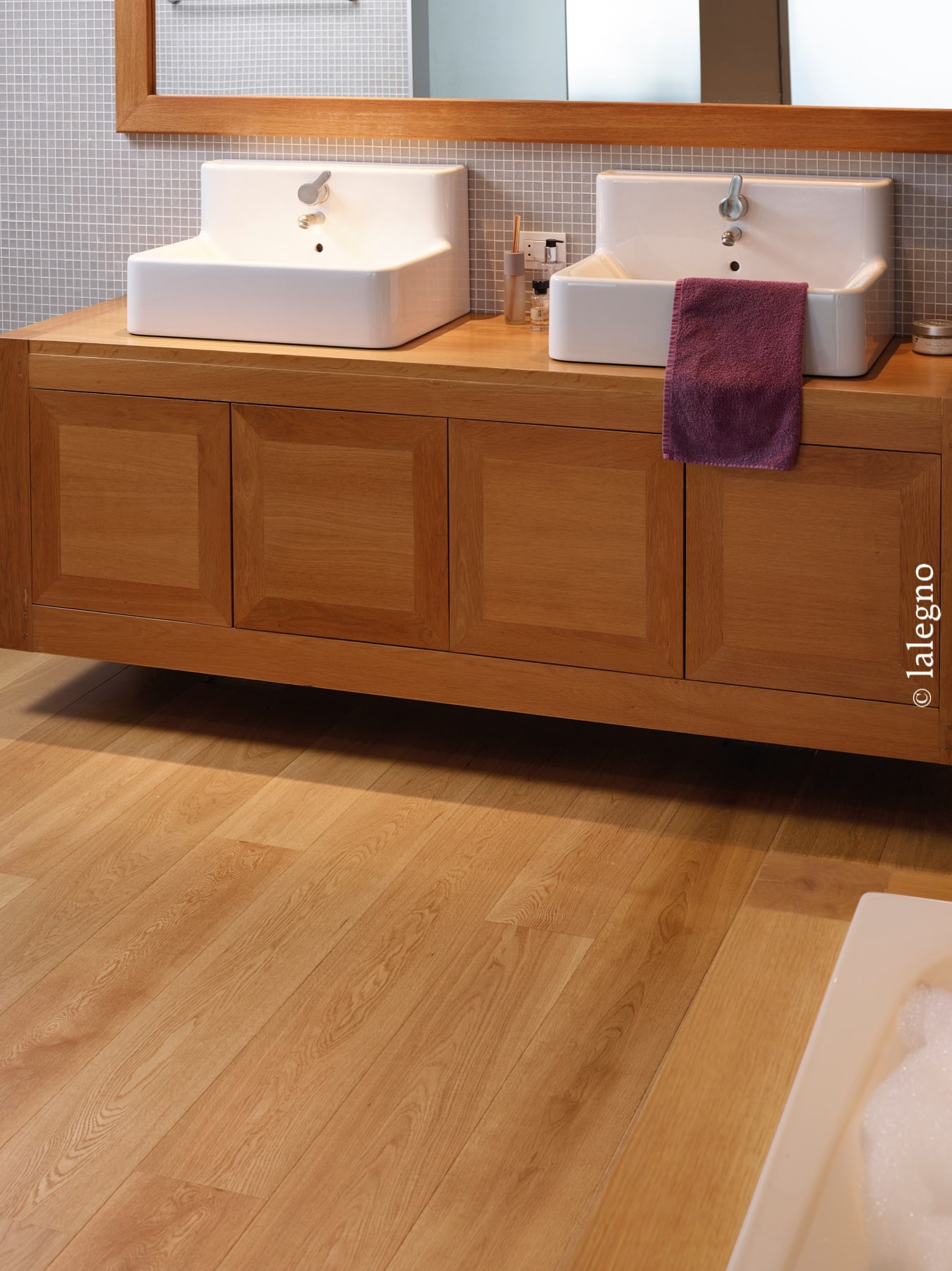 Meuble vasque flottant double en bois clair avec lavabos blancs. Parquet assorti et mosaïque grise. Texte : © lalegno.