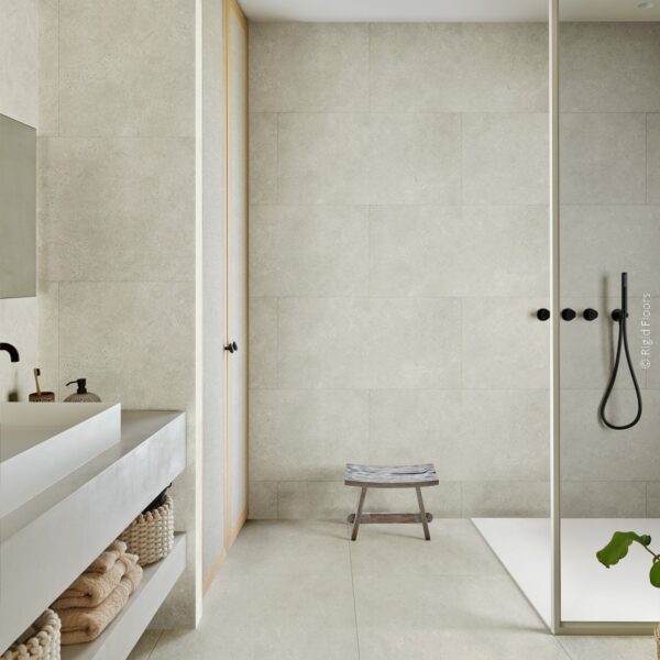 Grande salle de bain minimaliste. Carrelage gris clair au sol et murs. Douche italienne vitrée, meuble vasque en béton et rangements bois.