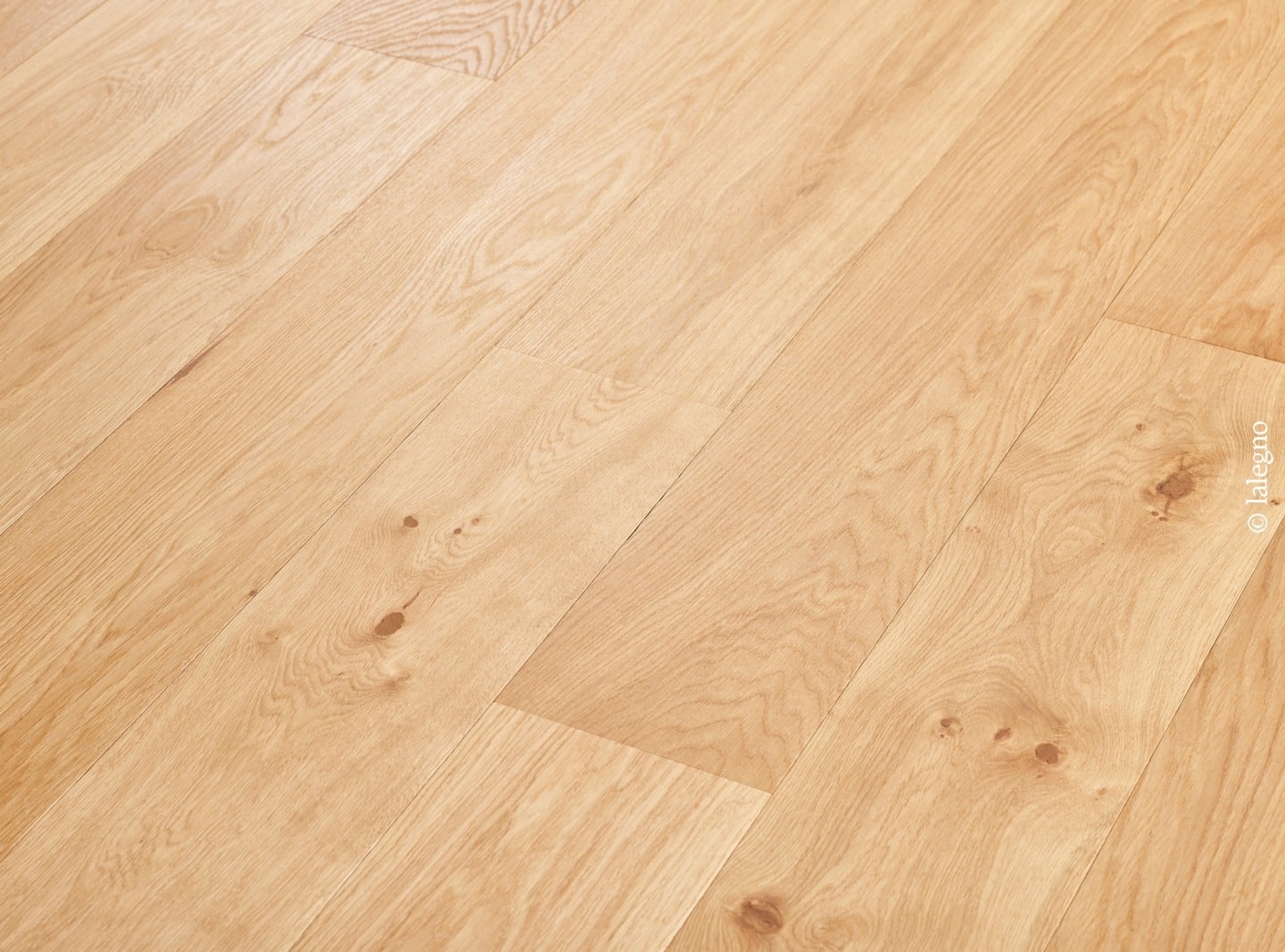 Parquet en chêne clair, lames larges et nœuds visibles, posé en diagonale. Bois naturel et chaleureux. Marque : lalegno.