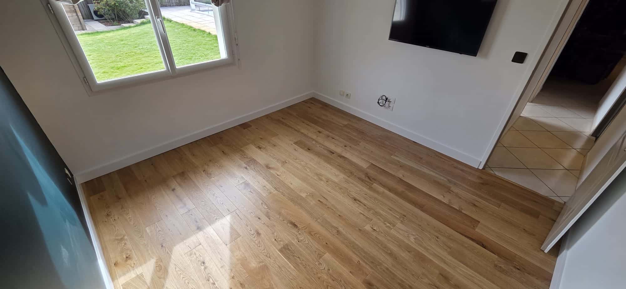 Parquet en Chêne Clair dans une Pièce Lumineuse et Moderne Parquet en chêne clair dans une pièce lumineuse avec murs blancs, fenêtre sur jardin et télévision murale.