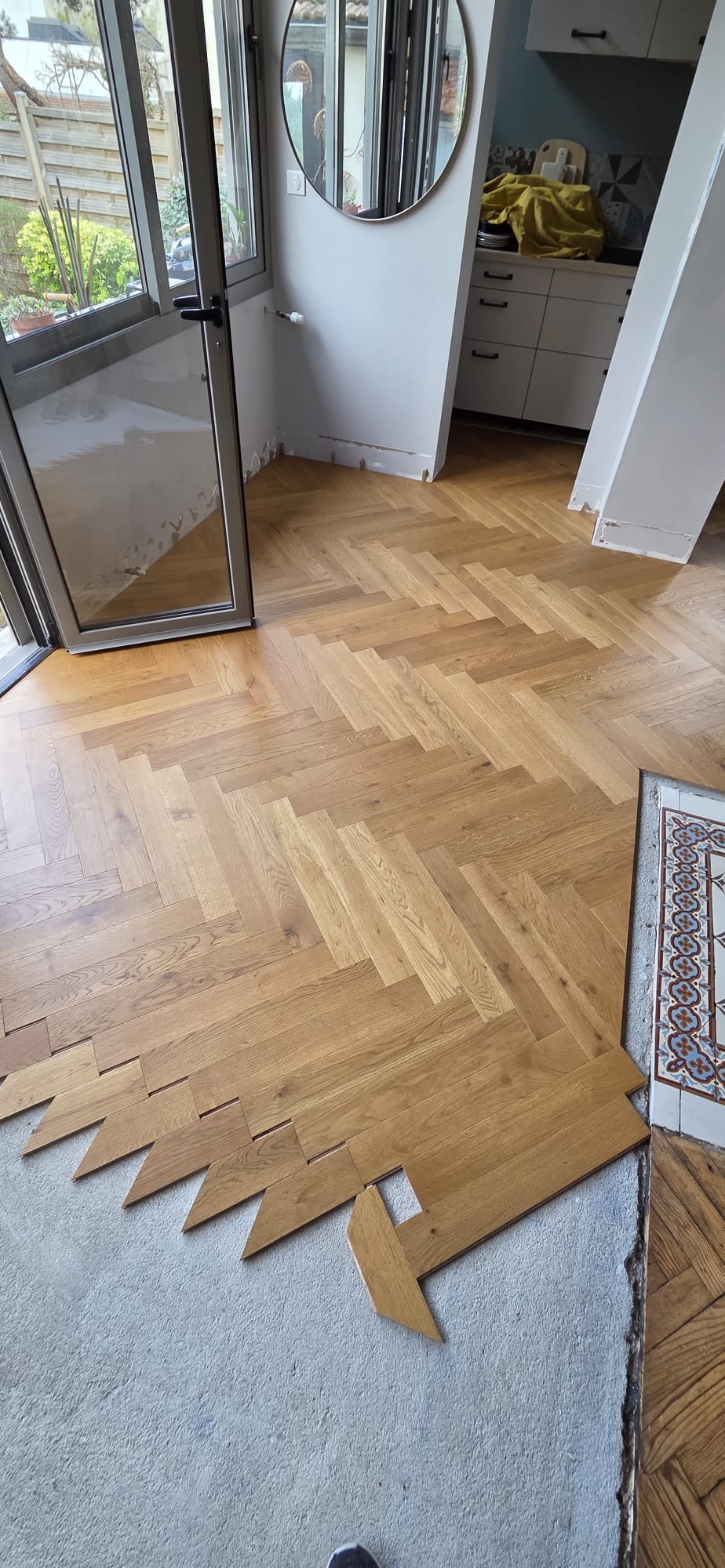 Pose d'un parquet en chêne massif à bâtons rompus sur un sol en béton en pleine rénovation intérieure.