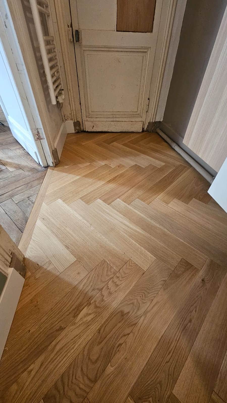 Parquet en chêne massif avec motif à chevrons, bois clair naturel installé lors d'une rénovation intérieure.