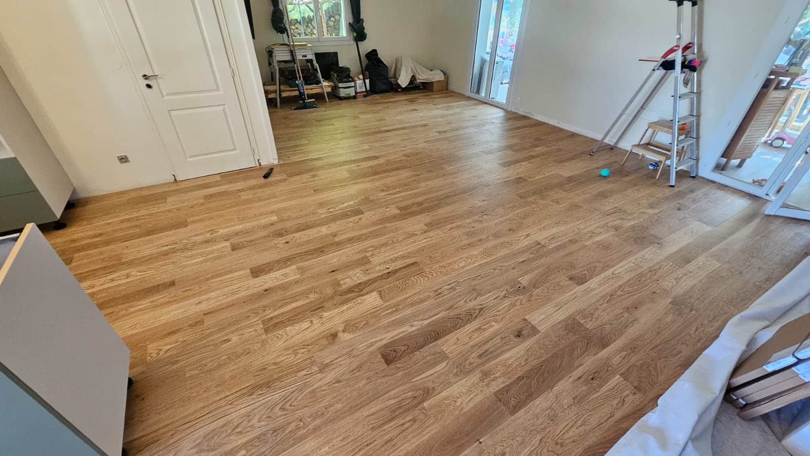 Pose de parquet en chêne massif clair dans un salon en rénovation, sol en bois naturel élégant et lumineux.