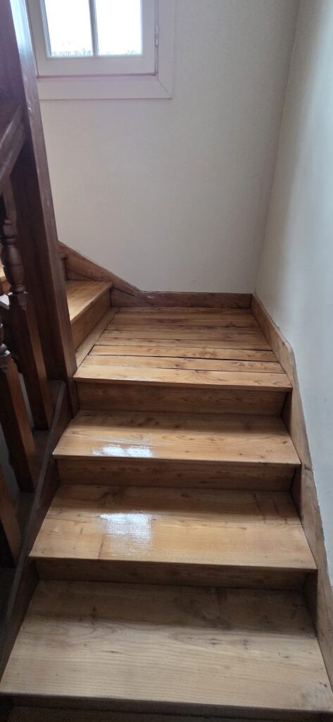Escalier en Bois de Pin Verni et Palier Lumineux Escalier intérieur en bois de pin verni menant à un palier lumineux dans une maison.