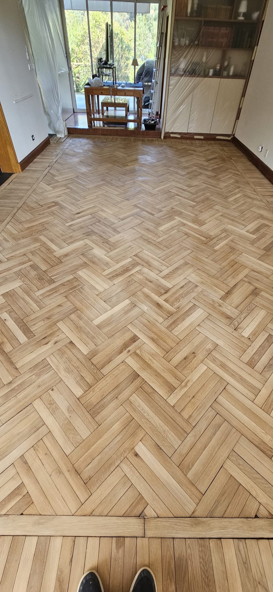 Parquet en bois clair motif bâtons rompus triples dans un salon lumineux avec bordures de finition élégantes.