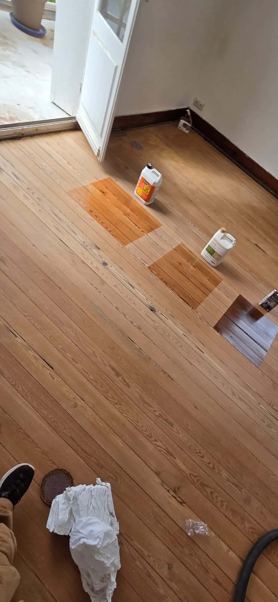 Trois tests de teinture sur un parquet ancien en bois avec bidons de finition Bona Domo lors d'une rénovation.