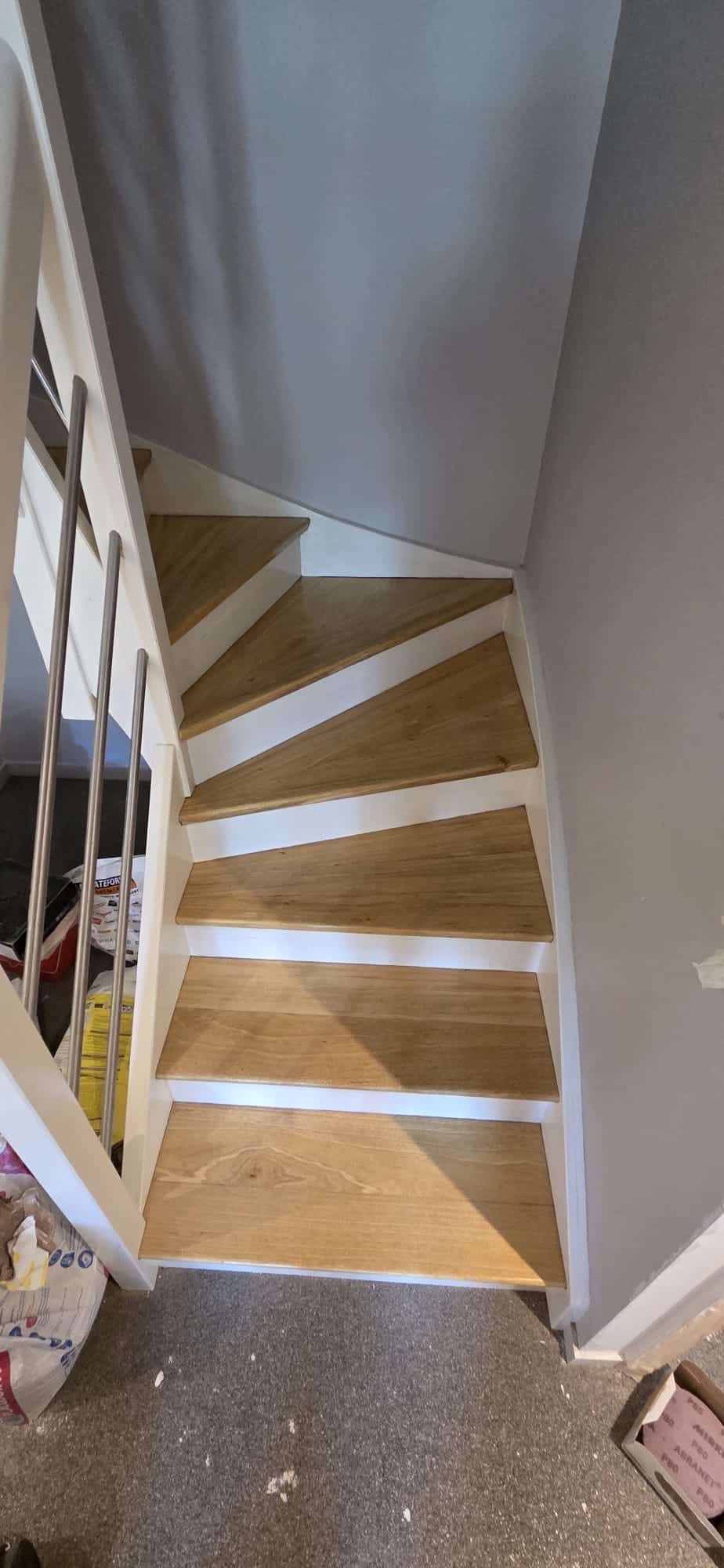 Escalier quart-tournant bois et blanc, balustrade inox, chantier intérieur.