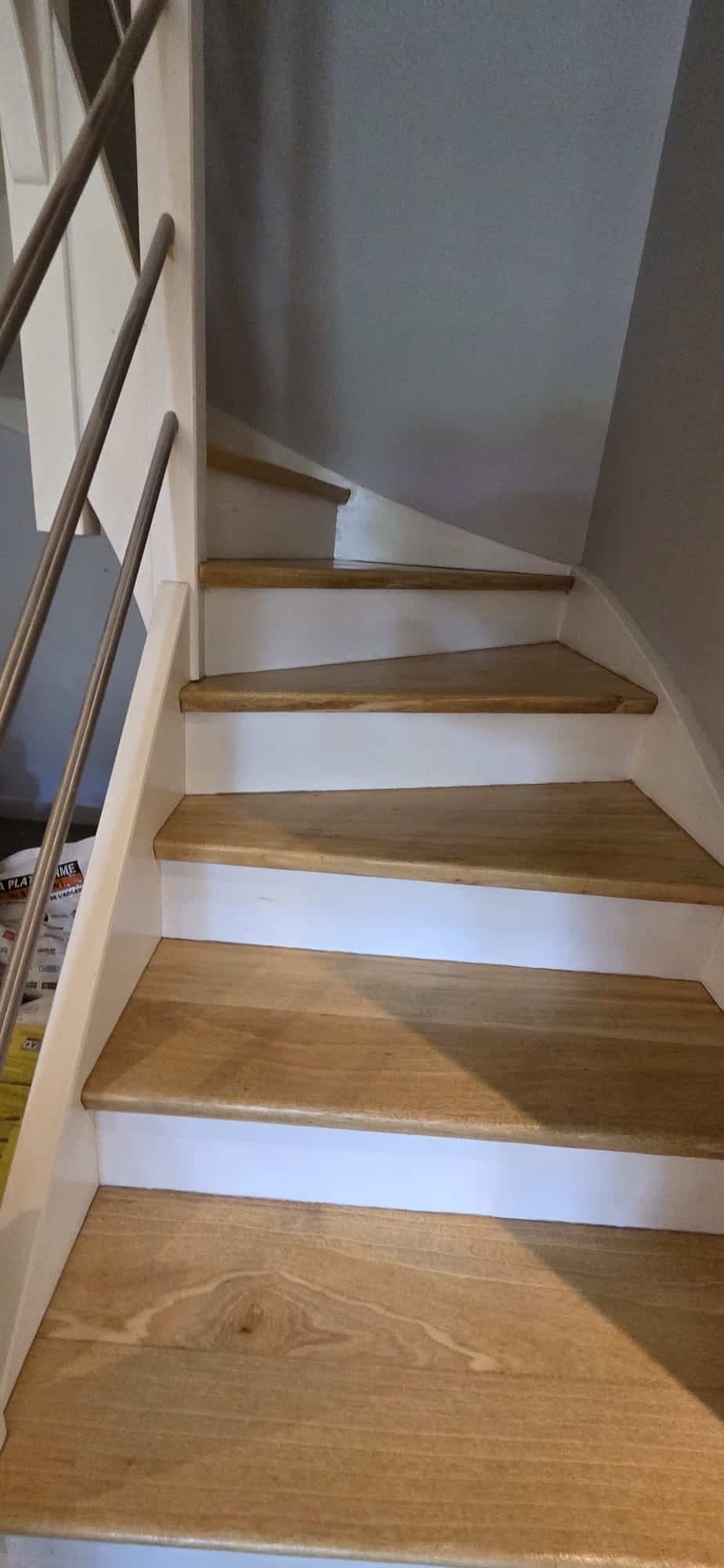 Escalier tournant en bois clair, marches chêne et contremarches blanches.