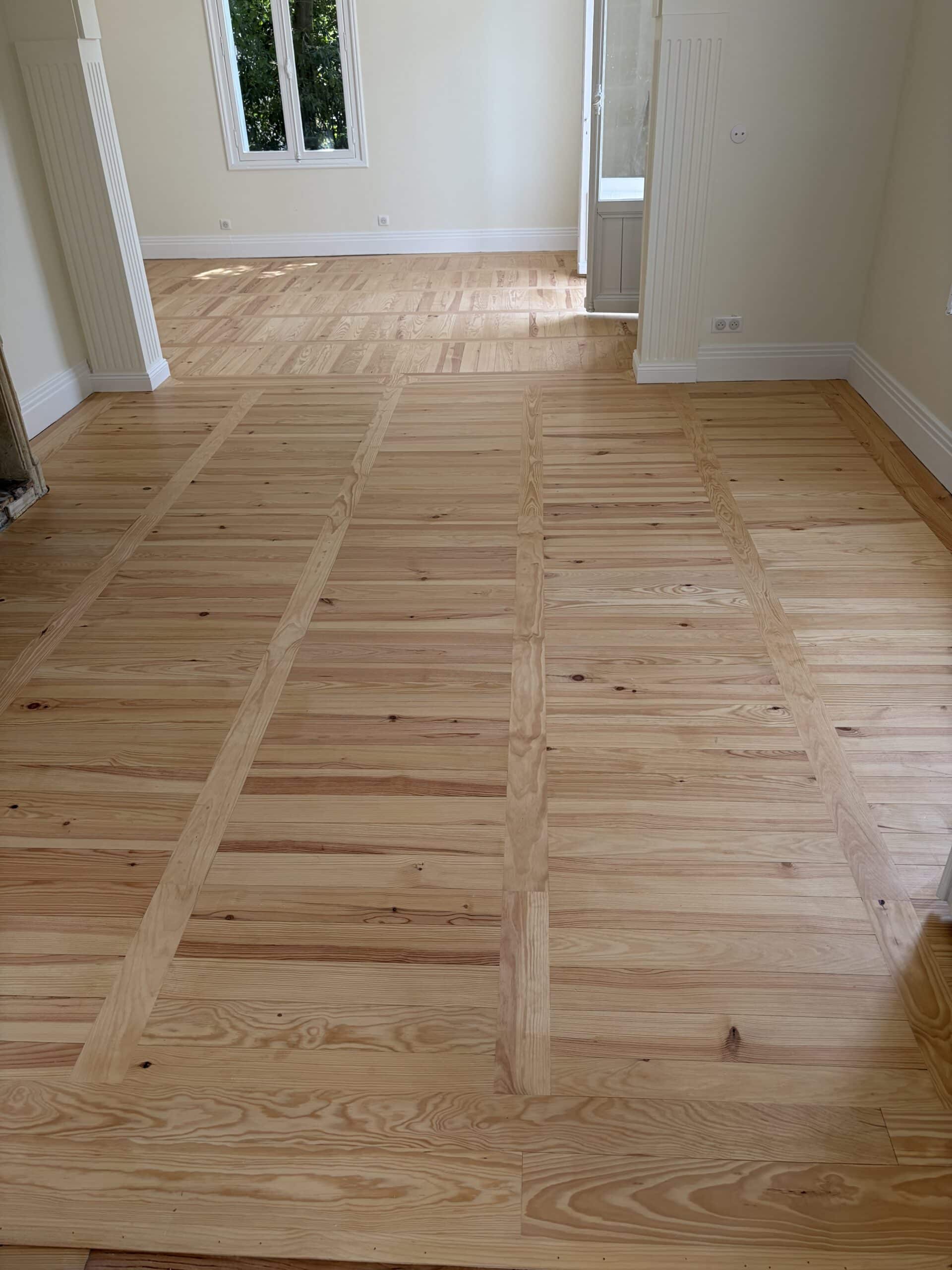 Parquet en Bois Clair avec Motif Géométrique Elégant Parquet massif en bois clair à motif géométrique dans un intérieur blanc avec colonnes cannelées.