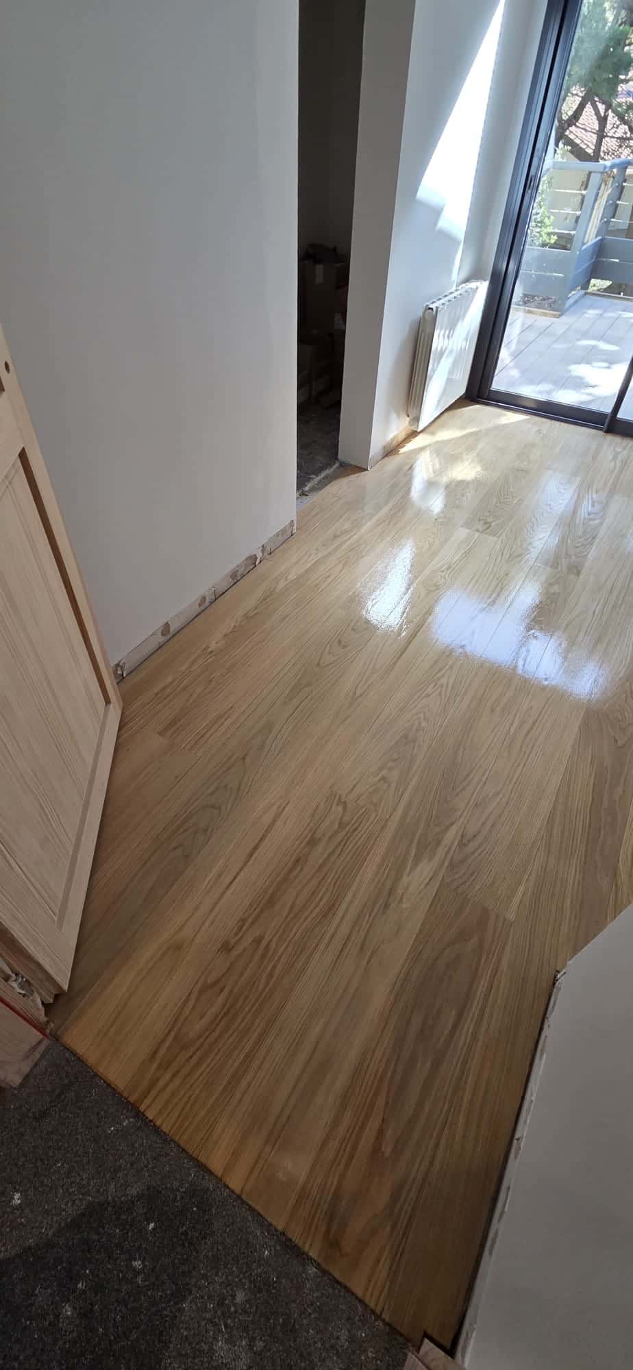 Parquet en chêne clair verni dans une pièce lumineuse en cours de rénovation.