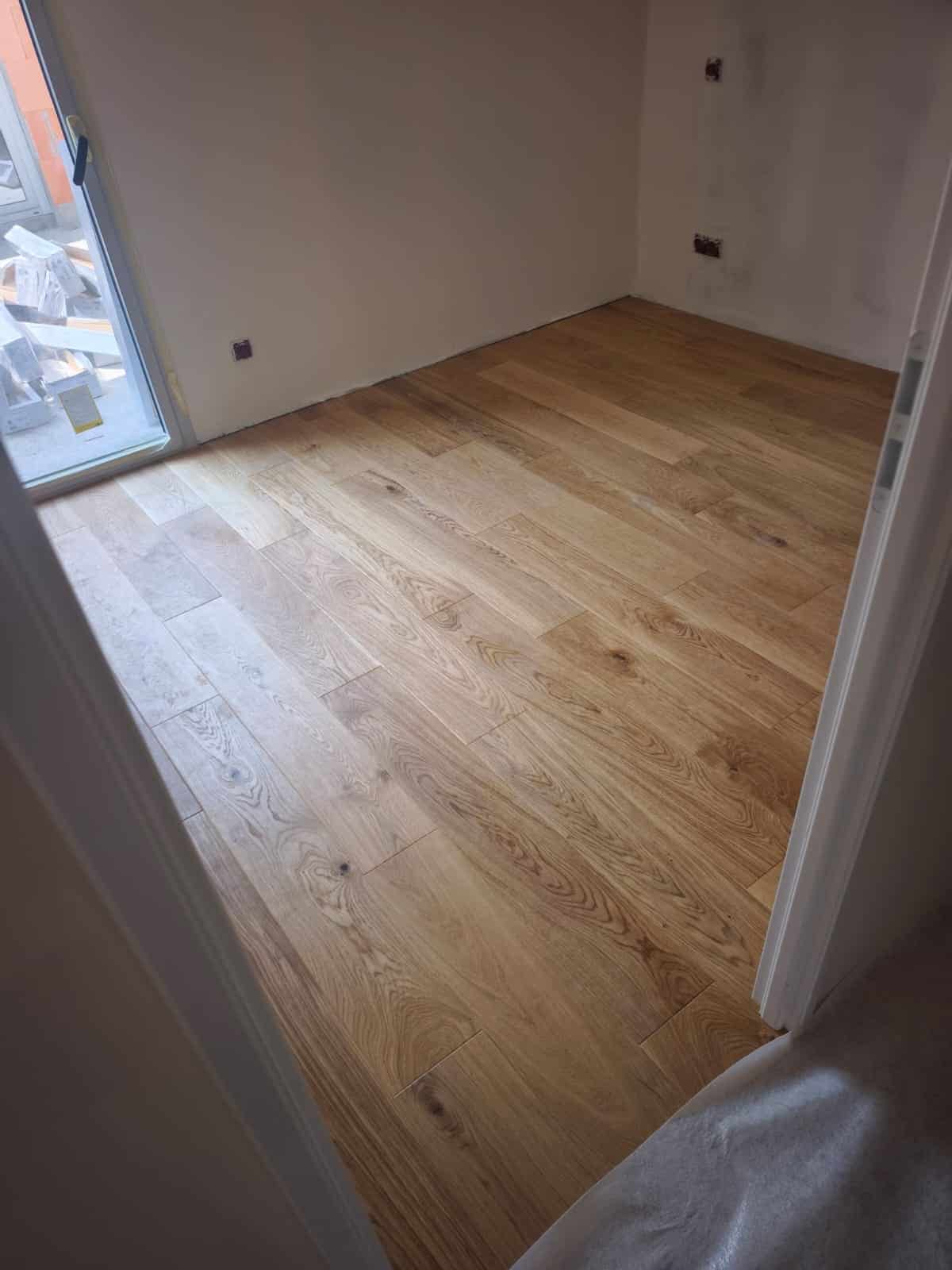 Parquet en chêne clair installé dans une pièce vide aux murs blancs en cours de rénovation.