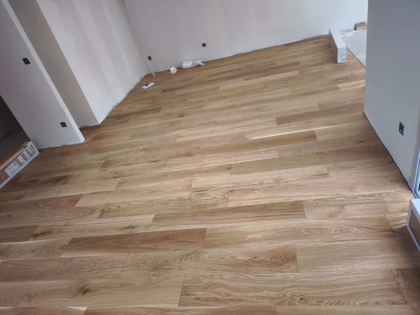 Parquet Chêne Massif : Pose et Rénovation Intérieure Parquet en chêne massif clair posé dans une pièce lumineuse en rénovation avec murs blancs.