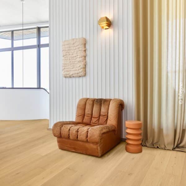 Salon design avec fauteuil cuir marron, parquet en chêne clair Lalegno et décoration murale texturée.